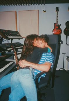 a man and woman cuddle in front of an electronic keyboard while sitting next to each other