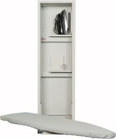 an ironing board is next to a white shelf with silver items on it and a black bag