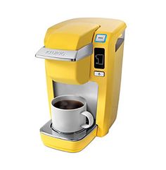 a yellow keurice coffee maker next to a cup of coffee