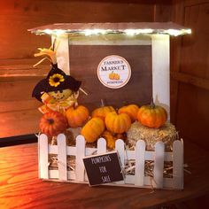 pumpkins and hay in a white crate on a wooden table with a sign that says pumpkin market