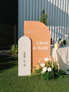 an orange sign sitting on top of a lush green field next to a white table