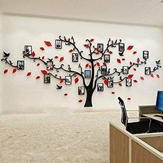 a tree with many pictures hanging on it's side in front of a computer desk