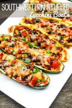 stuffed zucchini boats with black beans, tomatoes and green peppers on a white plate