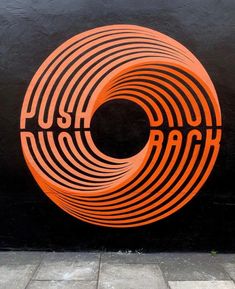 an orange sign that says push back on the side of a building in front of a black wall