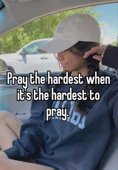 a woman sitting in the back seat of a car wearing a baseball cap and holding her head