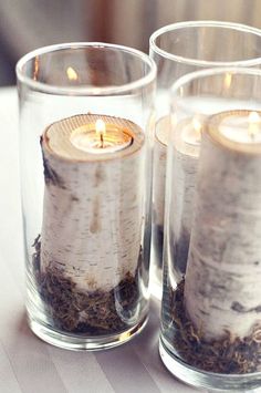 two glass vases filled with candles on top of a table