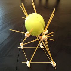 a green ball with sticks sticking out of it sitting on top of a black table