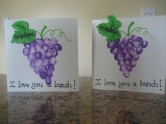 two greeting cards with grapes on them sitting on top of a granite countertop next to each other