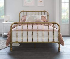 a bed with pink sheets and pillows in a room next to two pictures on the wall