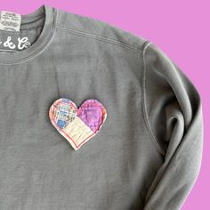 a gray sweatshirt with a heart patch on it