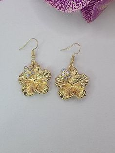 Pretty hibiscus flower earrings with crystal accents. Tarnish resistant ear hooks. 14kt Gold 'pinoy' /filipino Sunkiss Earrings, Elegant Flower Shaped Earrings For Beach, Elegant Flower-shaped Beach Earrings, Gold Beach Jewelry With Flower Charm, Gold Jewelry With Flower Charm For Beach, Elegant Dangle Flower Earrings For Beach, Elegant Flower-shaped Earrings For Beach, Gold Flower Jewelry For Beach, Gold Flower Earrings For Beach