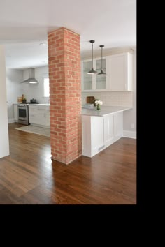 an empty kitchen and living room with wood floors in the middle is seen from across the room