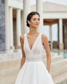 a woman standing in front of a building wearing a white dress