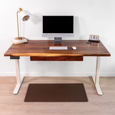 a wooden desk with a computer monitor and keyboard on it next to a brown mat