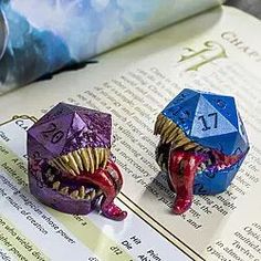 two origami monsters sitting on top of an open book next to each other