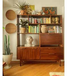 a bookshelf filled with lots of books next to a potted plant on top of a wooden table