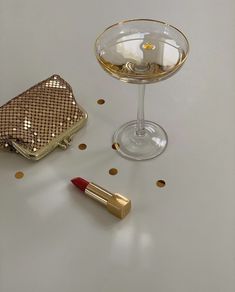 a small gold purse next to a wine glass with a red lipstick on the table