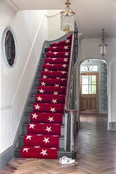 a red carpeted stair case with white stars on it and a chandelier hanging from the ceiling