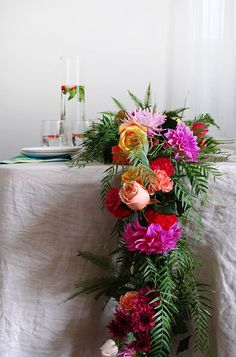 a vase filled with flowers on top of a table next to a plate and glassware