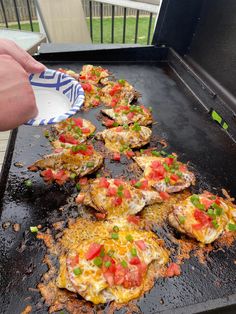 the food is being cooked on the grill with someone's hand reaching for it