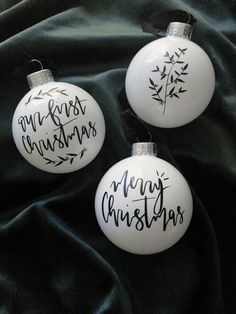 three white ornaments with black writing on them