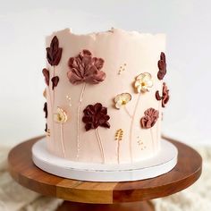 a pink cake decorated with flowers on a wooden stand