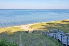 the stairs lead down to the beach from the grassy area next to the water's edge