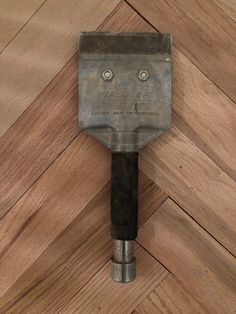 an old metal tool is laying on the floor with wood floors in the backround