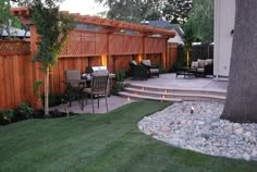 an outdoor patio and deck area with lights on the side, surrounded by grass and trees