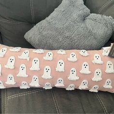 a pillow with ghost faces on it sitting on a couch next to a stuffed animal