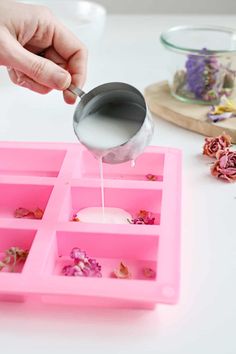 a person pouring tea into pink trays filled with flowers