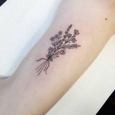 a flower tattoo on the left arm is shown in black and grey ink, with small flowers growing out of it