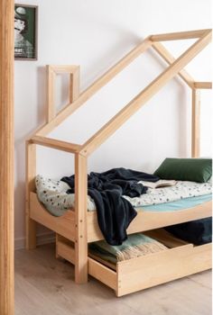 a bed frame with drawers underneath it in a room that has white walls and wooden floors