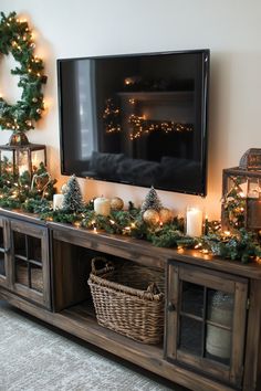 a christmas mantle with candles, wreaths and lights on it next to a flat screen tv