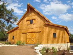 a large wooden barn with two doors and windows on the front, surrounded by trees