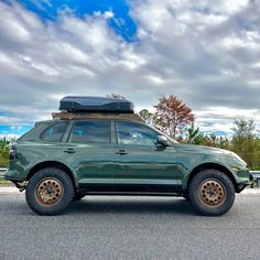 a green suv parked on the side of the road with its roof rack mounted to it's trunk