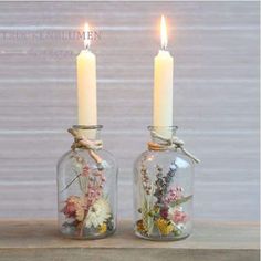 two glass jars with flowers and candles in them