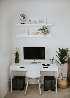 a white desk with a computer on it and some plants in front of the monitor