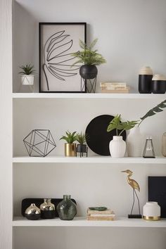 three white shelves with plants and vases on them, one is black and the other is gold