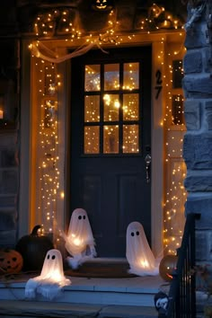 two ghost decorations on the front porch of a house decorated for halloween with fairy lights