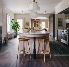 a kitchen with two stools at the center of the table and an island in the middle