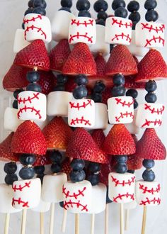 strawberries and blueberries are arranged on skewers with baseball pinstripes