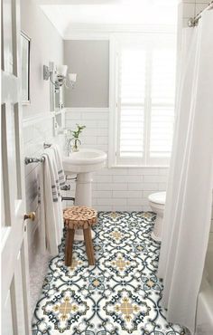 a white and blue tiled bathroom with a stool in the corner next to the shower