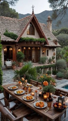 a table with plates of food on it in front of a house surrounded by greenery