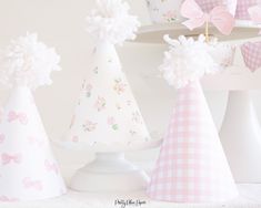 three paper hats with bows on them are sitting next to each other in front of a cake stand