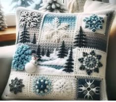 a crocheted snowman pillow sitting on top of a couch next to a window