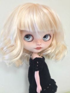 a doll with blonde hair wearing a black dress