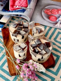 three desserts with ice cream and chocolate on a wooden platter next to pink flowers