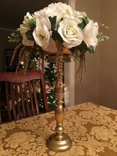 a vase with white flowers sitting on top of a table next to a christmas tree