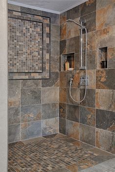 a walk in shower sitting next to a tiled wall and floor covered in brown tiles